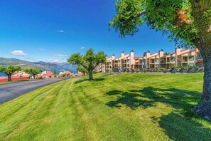 A hotel with a row of buildings, a well-maintained lawn, and a clear view of the mountains in the background. - Huge 1BR Lakefront 2nd-Floor - Balcony - Pool (Chelan)