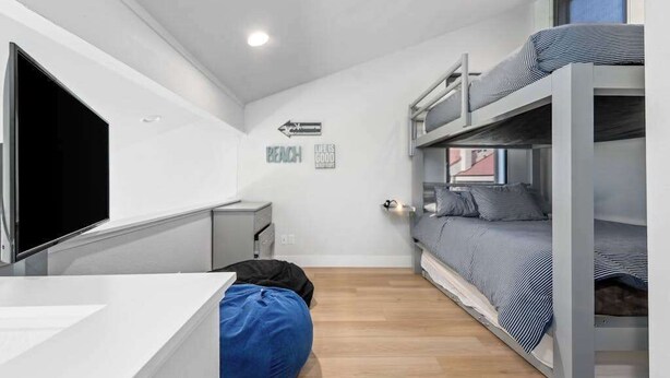 Ein kleines Zimmer mit Etagenbetten, einem Schreibtisch, einem Sitzsack und einem Fernseher.