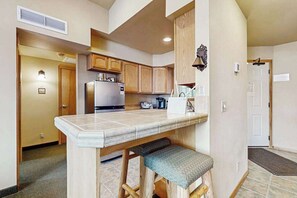 A compact kitchen with wooden cabinets, a built-in refrigerator, and a small island with a bench. - 2 BR condos located in the Icicle Resort (Leavenworth)