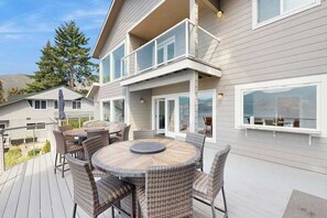 A deck with a round table and wicker chairs, overlooking a residential area. - Stunning 4BR Lakefront - Dock - Balcony (Manson)