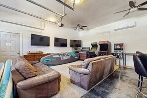 Ein Zimmer mit einer Sofagarnitur, einer Spielkonsole und einem Fernseher.