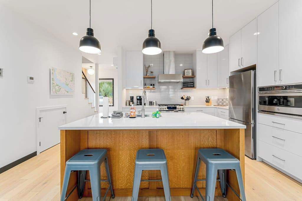 A modern kitchen with a central island, bar stools, and stainless steel appliances.