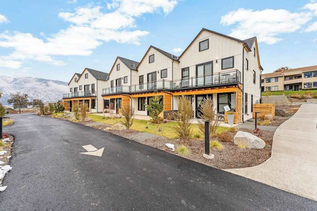 A modern residential building with multiple balconies and a paved driveway.