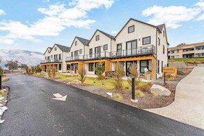 A modern residential building with multiple balconies and a paved driveway. - Modern 3BR Lakeview - Pool - Dock - Fireplace (Manson)