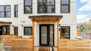 A modern building with a wooden entrance, a black door, and a welcome mat. - Modern 3BR Lakeview - Pool - Dock - Fireplace (Manson)