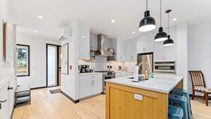 A modern kitchen with white cabinets, a central island, and pendant lighting. - Modern 3BR Lakeview - Pool - Dock - Fireplace (Manson)