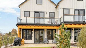 A two-story building with a balcony, large windows, and a covered patio area. - Modern 3BR Lakeview - Pool - Dock - Fireplace (Manson)