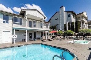 A swimming pool with a covered area, lounge chairs, and a building with a balcony. - 2BR Dog-Friendly - Pool (Chelan)