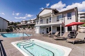 A residential area with a swimming pool, lounge chairs, and a hot tub.