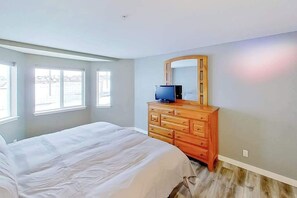 A bedroom with a bed, dresser, TV, and large windows. - 2BR Dog-Friendly - Pool (Chelan)