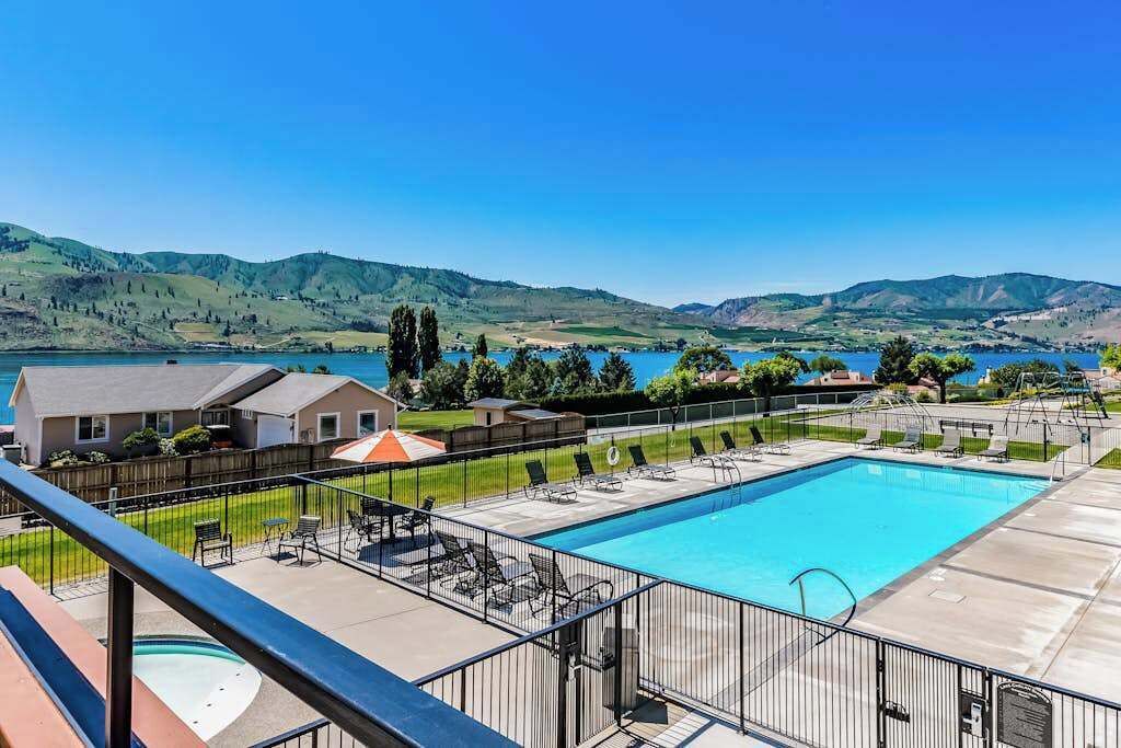 Une piscine dotée de chaises longues et offrant une vue sur un lac et des collines.