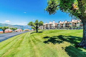 A hotel with a row of rooms, a grassy lawn, and a mountain view. - 1BR Lakeview 2nd-Floor - Balcony - Pool (Chelan)