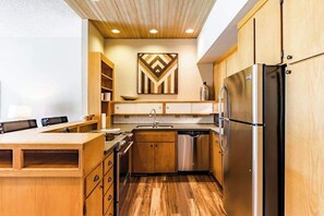 A kitchen with wooden cabinets, a stainless steel refrigerator, and a dishwasher.