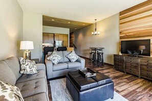 Ein modernes Wohnzimmer mit einer Couch, einem Hocker und einem Fernseher.