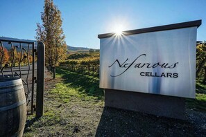 A sign for Nefarious Cellars with a vineyard in the background.