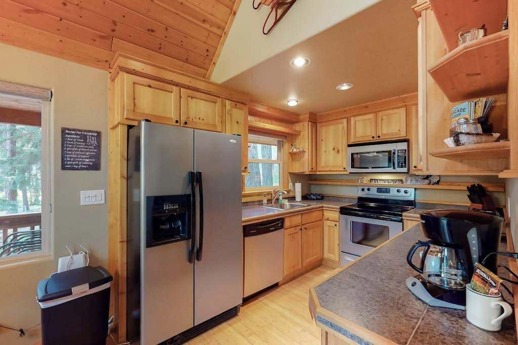 A kitchen with wooden cabinets, a stainless steel refrigerator, a microwave, an oven, and a coffee maker.