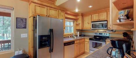 A kitchen with wooden cabinets, a stainless steel refrigerator, a microwave, an oven, and a coffee maker.