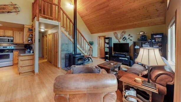 A spacious living area with a fireplace, wooden flooring, and a staircase leading to an upper level. - Secluded 3BR Mountainview - Hot Tub - WoodStove (Leavenworth)