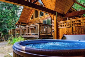 A wooden cabin with a hot tub, deck, and multiple windows. - Secluded 3BR Mountainview - Hot Tub - WoodStove (Leavenworth)