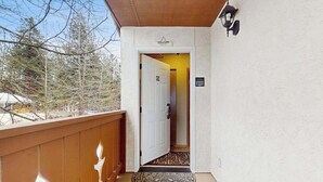 Ein Holzbalkon mit einer weißen Tür, die zu einem Flur führt.