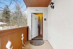 Ein Holzbalkon mit einer weißen Tür, die zu einem Flur führt.