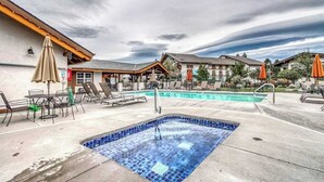 Ein Hotelpoolbereich mit Whirlpool, Liegestühlen und Sonnenschirmen.