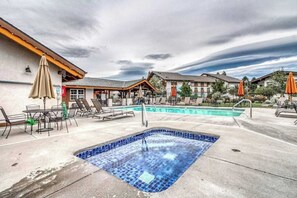 Ein Hotelpoolbereich mit Whirlpool, Liegestühlen und Sonnenschirmen.
