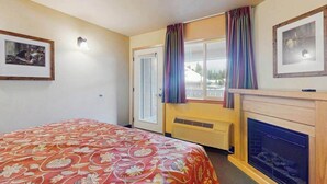 Ein Hotelzimmer mit einem Bett, einem Kamin, einem Fenster mit Vorhängen und einer wandmontierten Lampe.