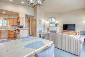 A compact living space with a dining table, sofa, TV, and kitchenette. - Downtown 2BR Mountainview 2nd-Floor - Balcony (Leavenworth)
