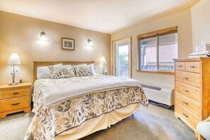 A bedroom with a large bed, bedside lamps, a dresser, and a window with a view. - Downtown 2BR Mountainview 2nd-Floor - Balcony (Leavenworth)