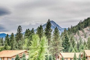 A mountain lodge with multiple cabins, surrounded by dense forest and a prominent mountain peak. - Downtown 2BR Mountainview 2nd-Floor - Balcony (Leavenworth)