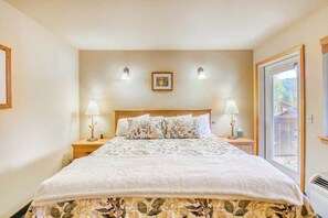 A bedroom with a large bed, two bedside tables with lamps, a window, and a picture on the wall. - Downtown 2BR Mountainview 2nd-Floor - Balcony (Leavenworth)