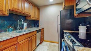 A kitchen with wooden cabinets, a stainless steel refrigerator, and a black stove. - Lovely Studio Mountainview - Patio - Pool (Chelan)