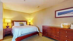 A hotel room with a bed, bedside lamps, a wooden dresser, and a framed picture on the wall. - Lovely Studio Mountainview - Patio - Pool (Chelan)