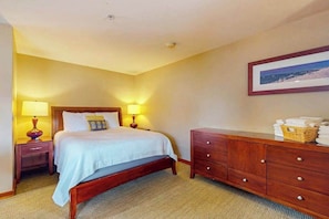 Ein Hotelzimmer mit einem Bett, Nachttischlampen, einer Holzkommode und einem gerahmten Bild an der Wand.