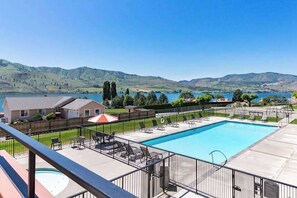 Ein Pool mit Liegestühlen und Blick auf Hügel und einen See.