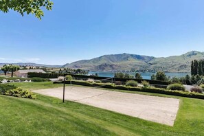 Un court de tennis offrant une vue sur un lac et des montagnes.