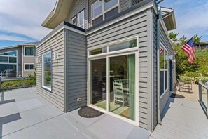 Ein zweistöckiges Haus mit überdachter Terrasse und Schiebetür.