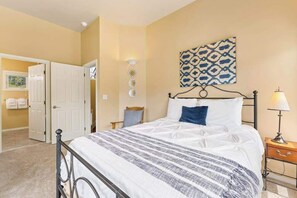 A bedroom with a bed, a nightstand, a lamp, a wall-mounted light fixture, and a door leading to another room. - Hip 4BR Lakeview - Pool - Hot Tub - Deck (Manson)