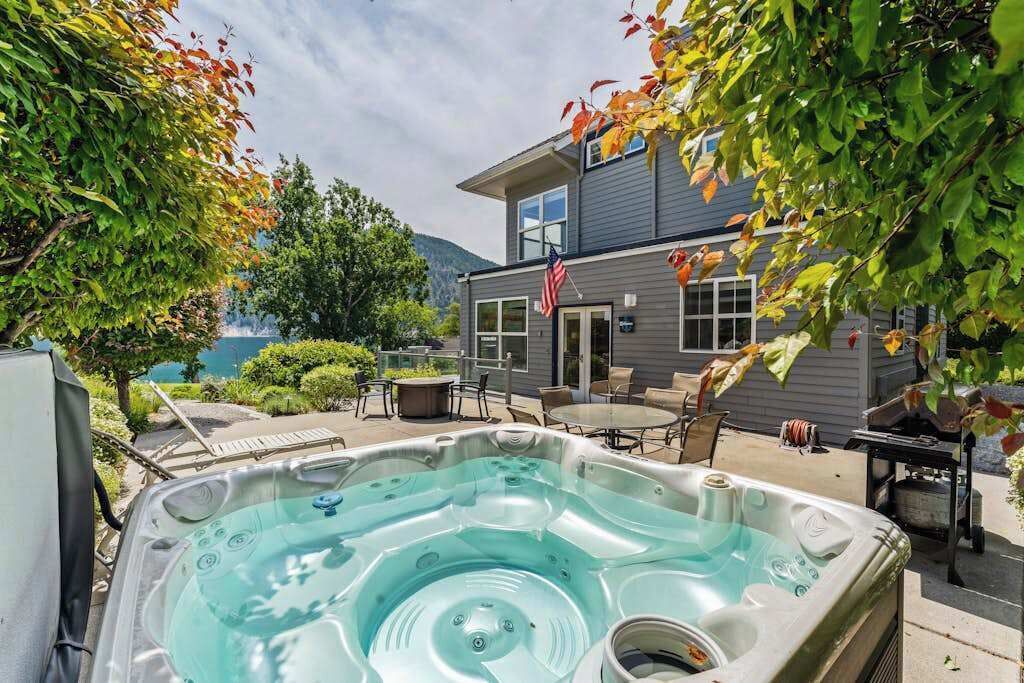 Un bain à remous dans un jardin, avec une maison et des arbres en arrière-plan.