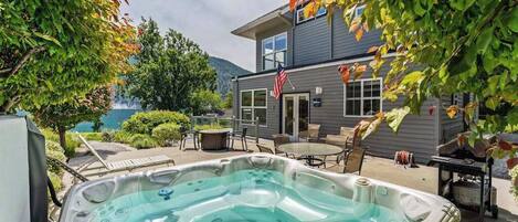 A hot tub in a backyard with a house and trees in the background.