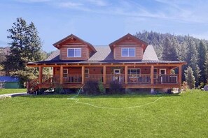 A two-story log cabin with a covered porch and a fenced yard. - 3BR mountain-view (Leavenworth)