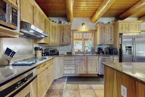 A kitchen with wooden cabinets, stainless steel appliances, and a granite countertop. - 3BR mountain-view (Leavenworth)