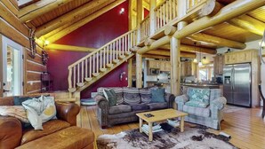 Ein geräumiger Wohnbereich mit einer Holztreppe, Ledersofas und einer Küche im Hintergrund.