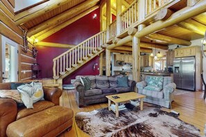 Ein geräumiger Wohnbereich mit einer Holztreppe, Ledersofas und einer Küche im Hintergrund.