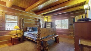 Ein Schlafzimmer in einer Blockhütte mit einem hölzernen Bett, einer Bank und einer Lampe.