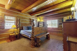 Ein Schlafzimmer in einer Blockhütte mit einem hölzernen Bett, einer Bank und einer Lampe.