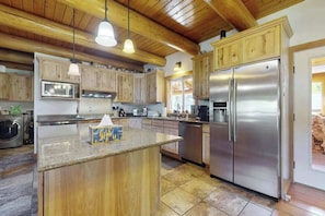 A kitchen with wooden cabinets, a stainless steel refrigerator, and a granite countertop.