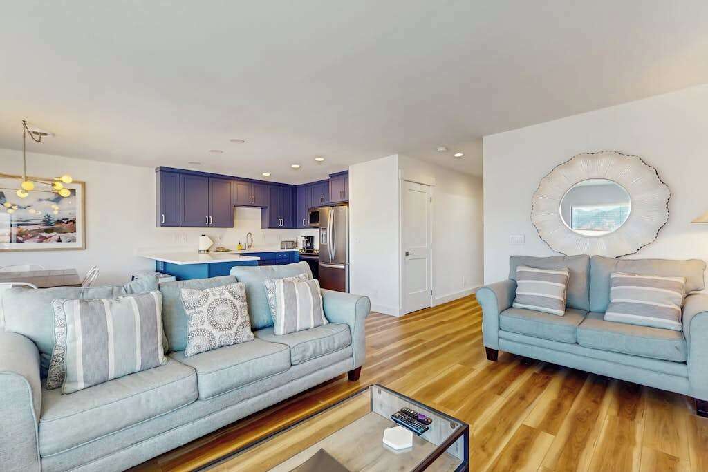 A modern living room with a sofa, a coffee table, and a kitchen in the background.