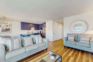 A modern living room with a sofa, a coffee table, and a kitchen in the background. - Large 2BR Lakeview 1st-Floor - Balcony - Pool (Chelan)